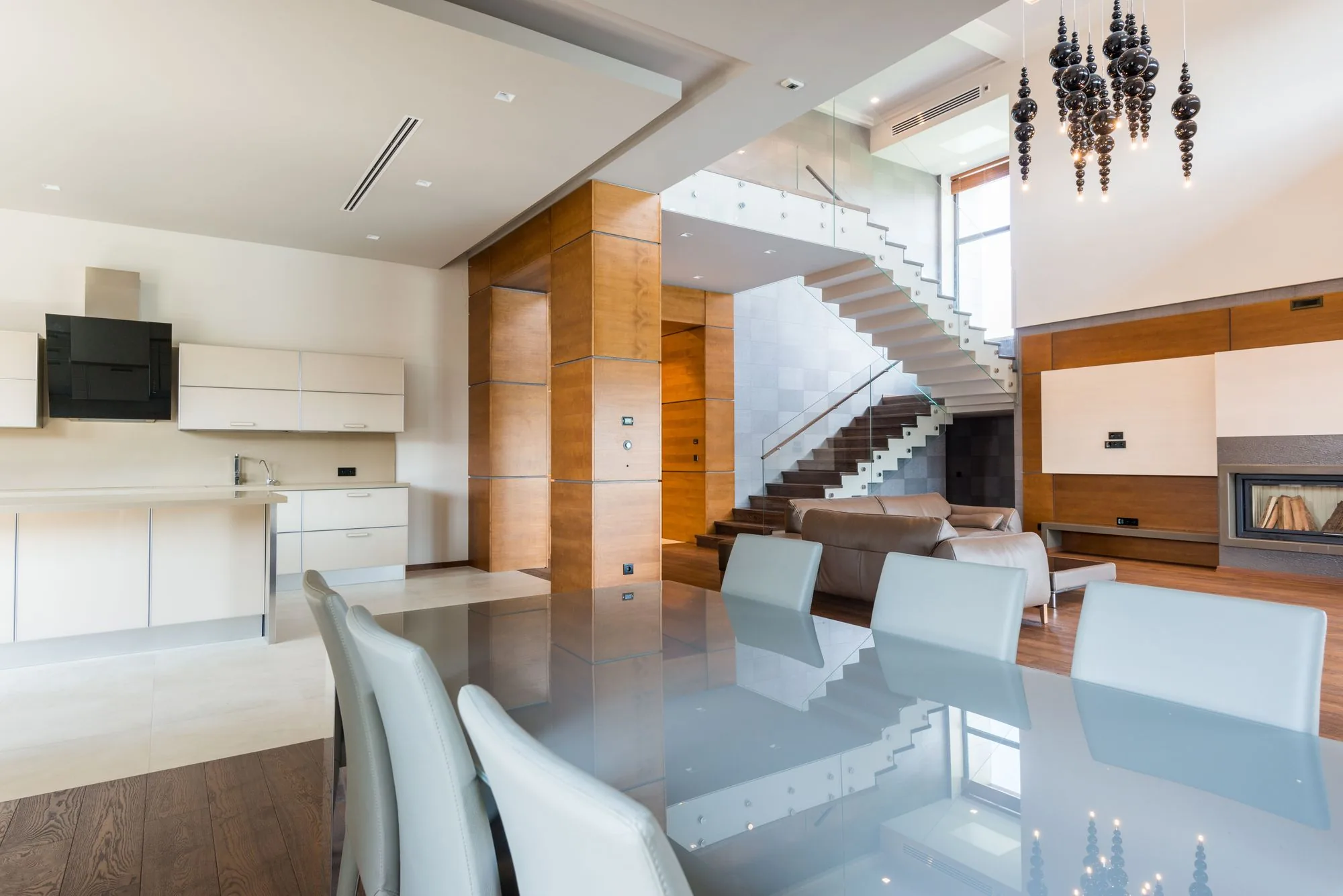 Comedor con mesa de cristal y escalera al fondo